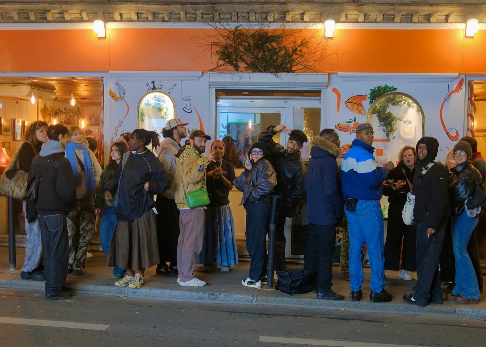 Foule rassemblée devant une vitrine orange, un soir d’événement