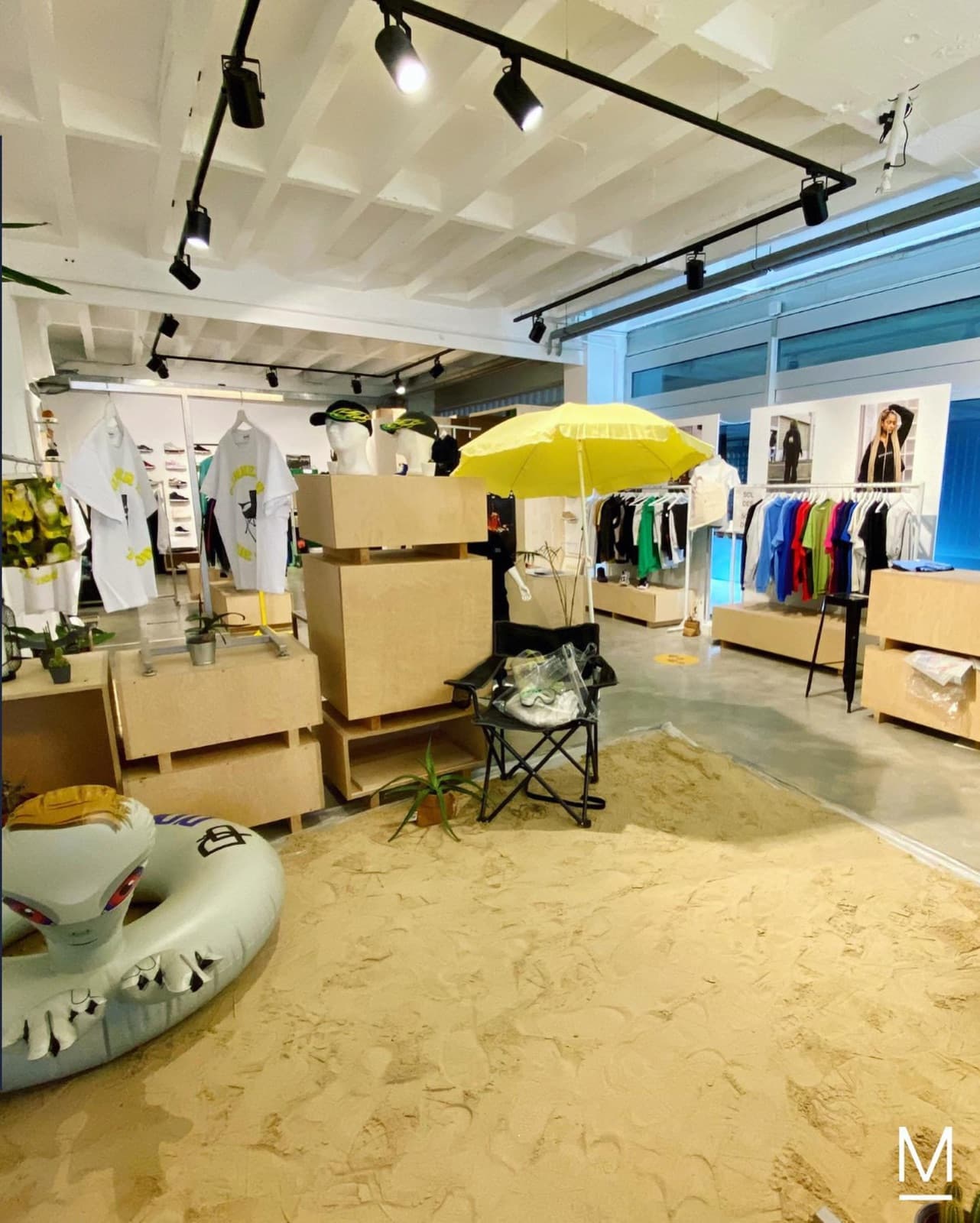 Boutique Memories : portants, parasol jaune et sable au sol