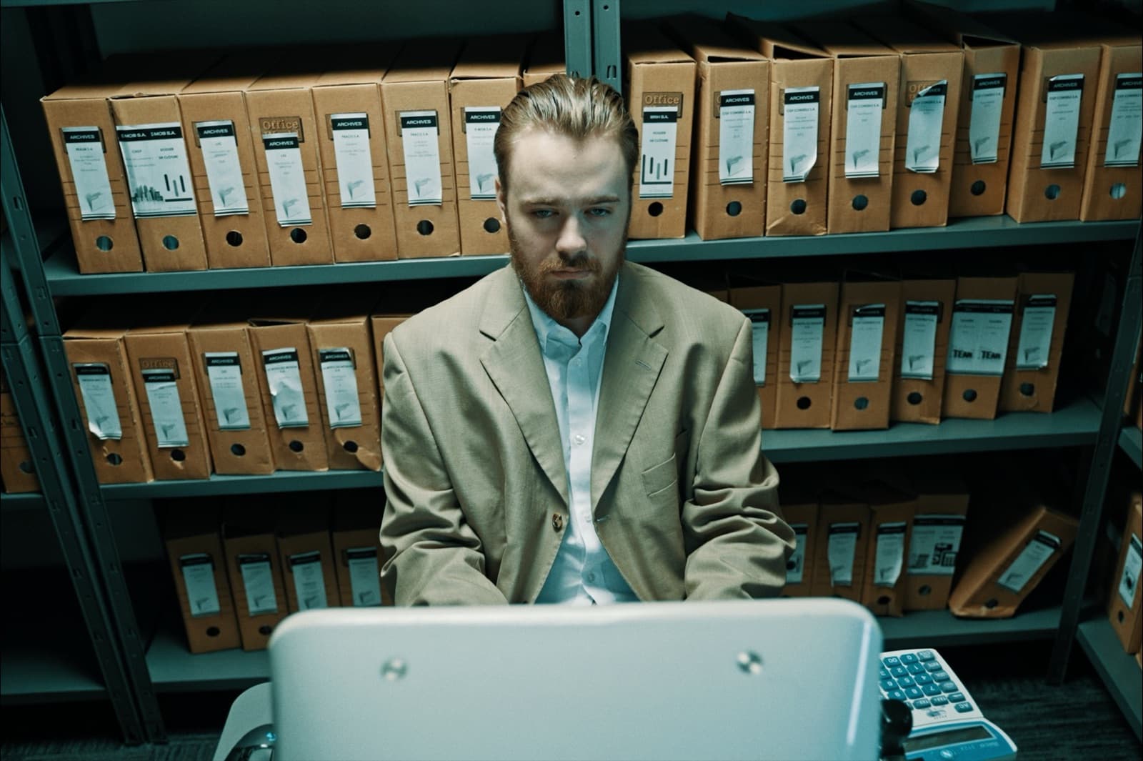Ant — un homme en costume dans un bureau rempli de cartons